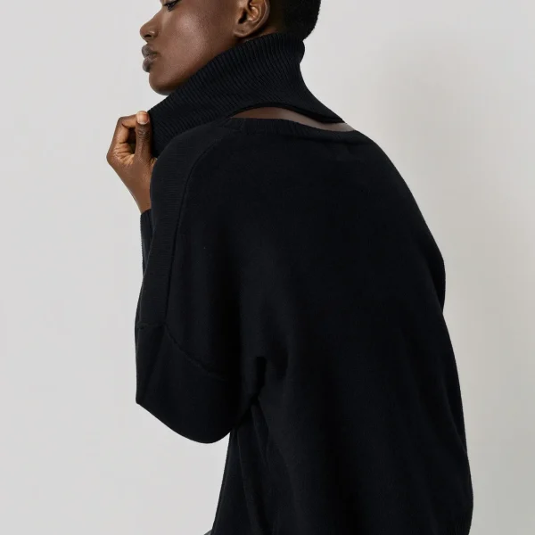Jersey oversize de cuello alto negro BSB, lateral con la modelo sentada