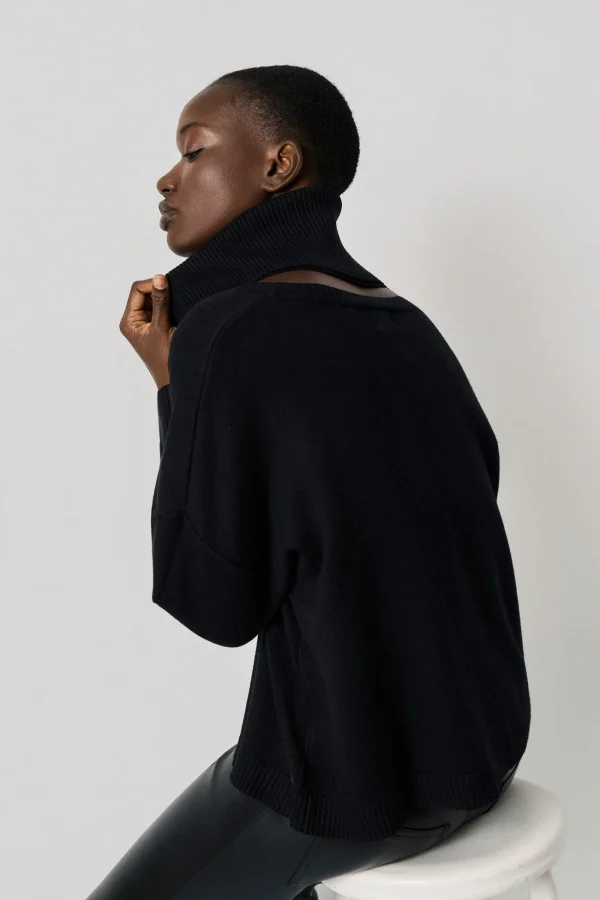 Jersey oversize de cuello alto negro BSB, lateral con la modelo sentada