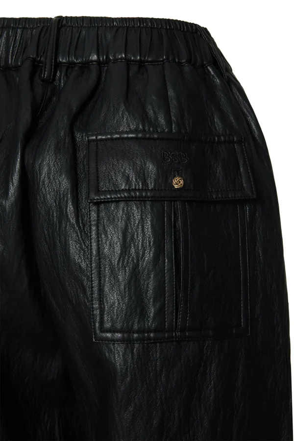 Detalle del bolsillo trasero con botón dorado del pantalón de polipiel negro BSB Detalle del bolsillo trasero con botón dorado del pantalón de polipiel negro BSB