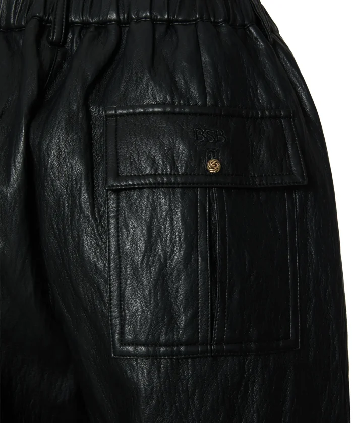 Detalle del bolsillo trasero con botón dorado del pantalón de polipiel negro BSB