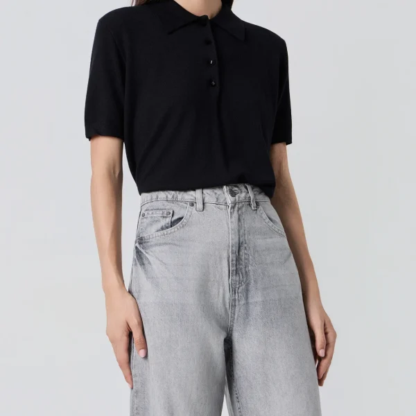 Polo de punto negro BSB, de frente con cuello camisero y vaqueros grises Polo de punto negro BSB, de frente con cuello camisero y vaqueros grises