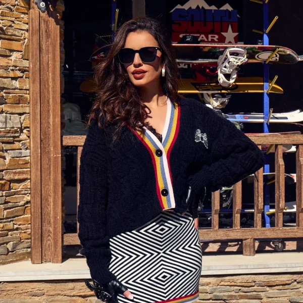 Cardigan Kaelen Camaleónica · exterior frontal Cárdigan Kaelen de Camaleónica negro abotonado, con ribete de rayas de colores, combinado con falda Brim.