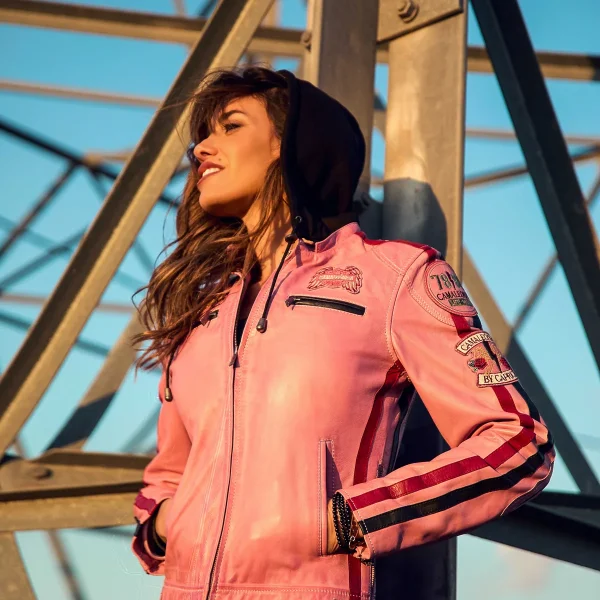 Chaqueta Runak Camaleónica · exterior frontal Chaqueta Runak de Camaleónica de piel rosa con capucha negra, fotografiada al aire libre.
